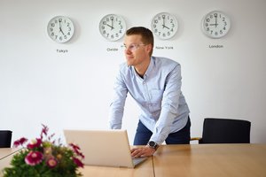 Venti Oelde 的一名员工在象征 "国际化 "护栏的四个时区的时钟前合影